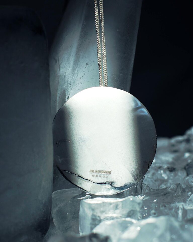 Close-up of a shiny silver pendant among ice, exuding purity and elegance.